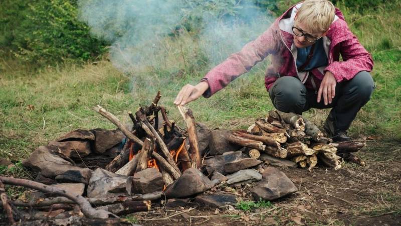 bushcraft feuerstelle mit steinen frau