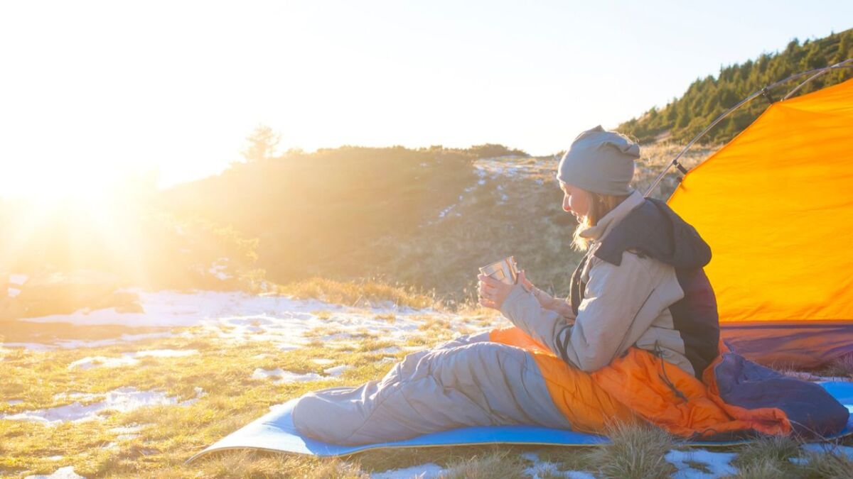 isomatte auf gras und schnee mit frau und zelt