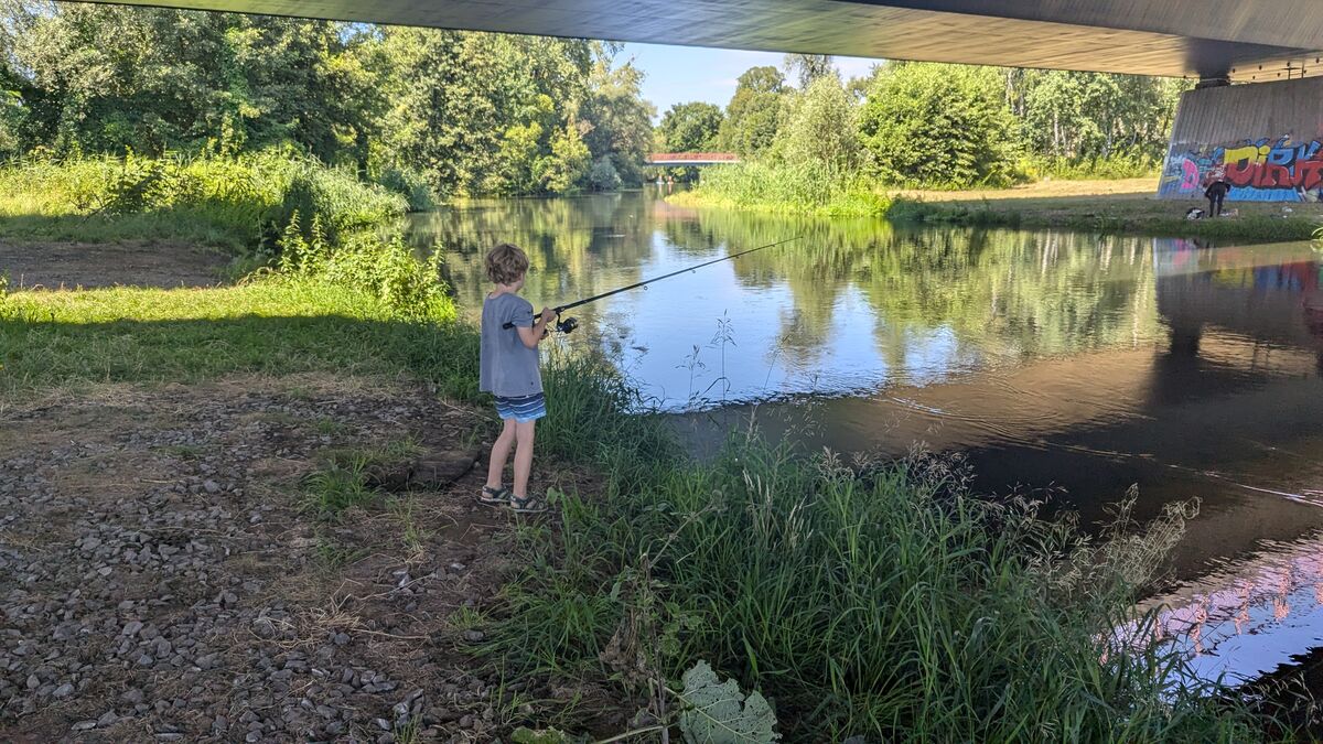 child fishing under bridge