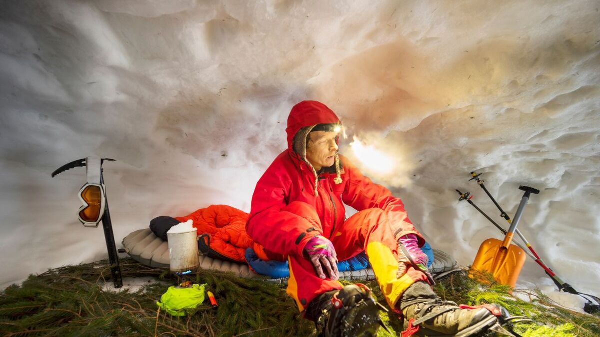 mann sitzt in schneehoehle