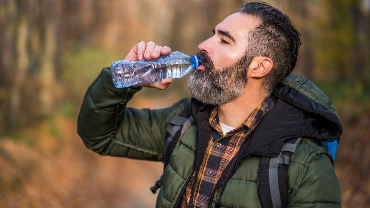 mann trinkt im wald aus wasserflasche