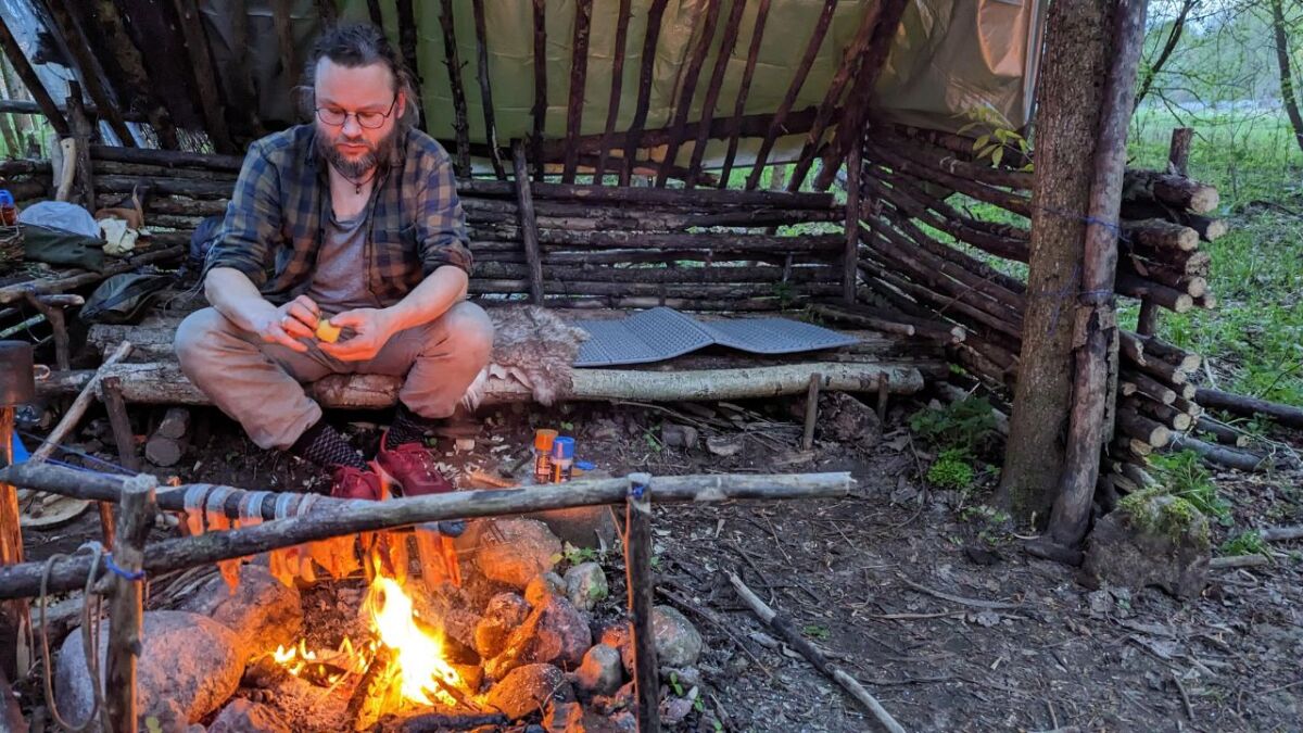 Ich warte in meinem kleinen Camp am Lagerfeuer auf die Teilnehmenden