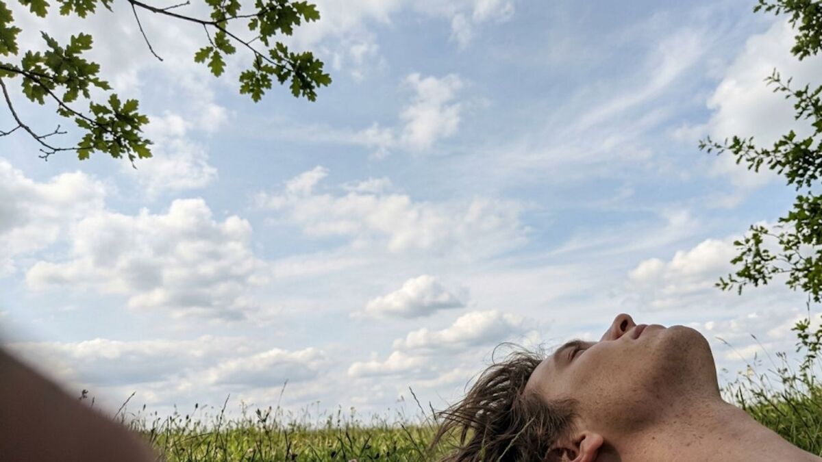person liegt wiese himmel schauen