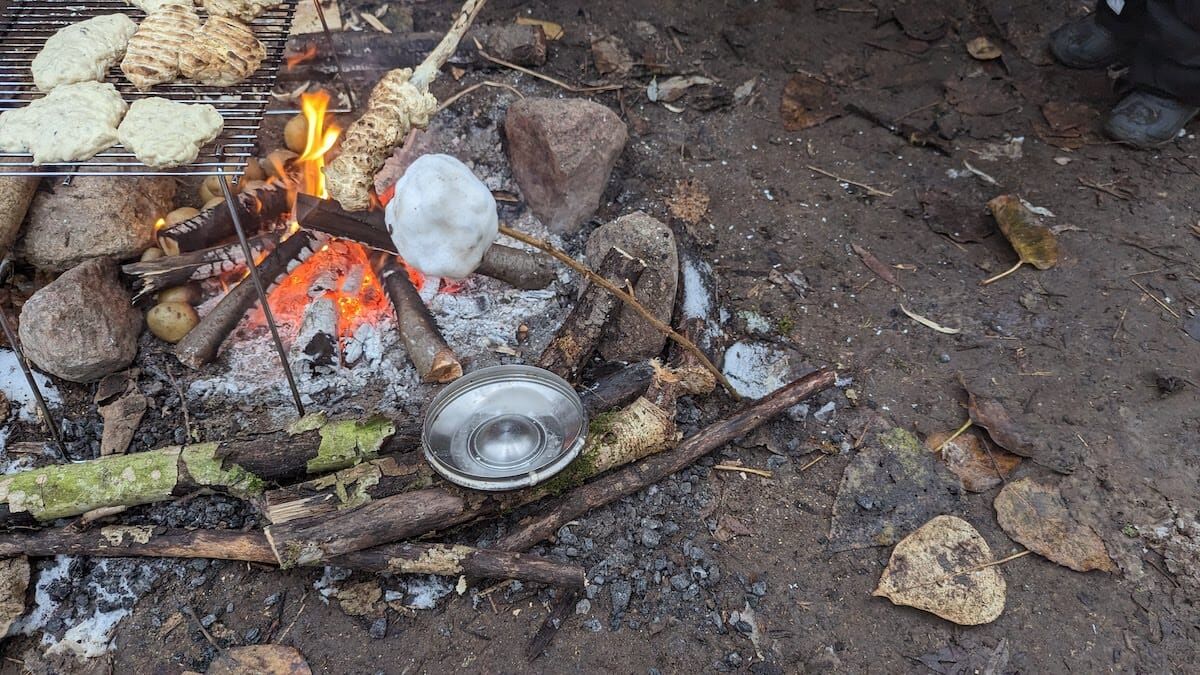 Melting snow on a stick next to the fire