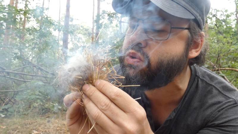 Here I am blowing on a tinder nest that I previously filled with an ember from the bow drill